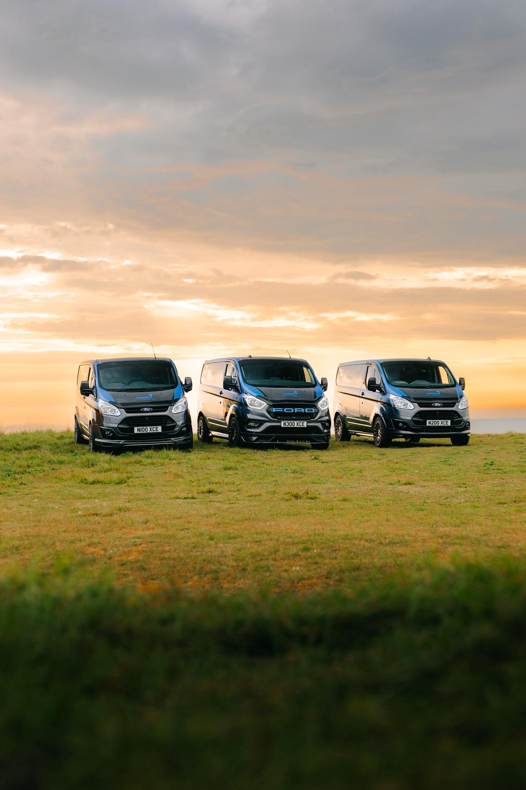 Three vans against a sunset sky